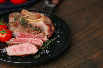 Pieces of delicious beef meat, spices and tomatoes on wooden table, closeup. Space for text