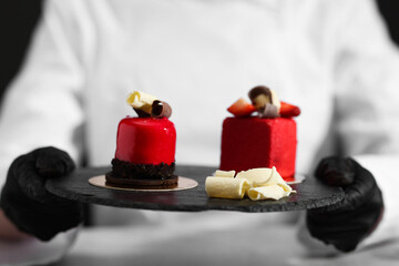 Confectioner with tasty desserts in kitchen, closeup