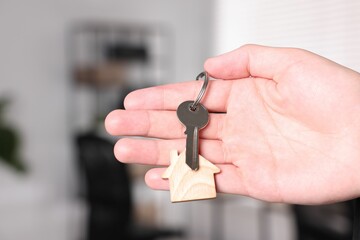 Real estate agent with house key indoors, closeup