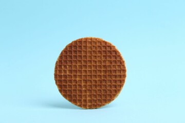 One tasty round waffle on light blue background