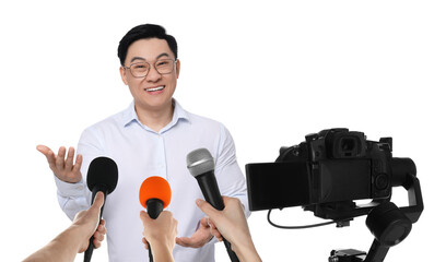 Journalists with microphones and video camera interviewing man on white background, closeup