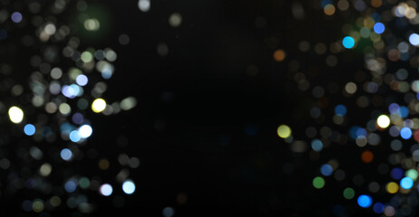 Blurred sparkling glitter on black background, bokeh. Abstract festive backdrop. Banner design with...
