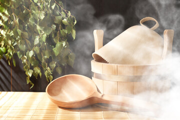 Sauna equipment. Bucket, felt wool hat and ladle on bamboo bench in steam