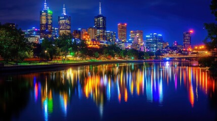 Obraz premium A vibrant city skyline at night with skyscrapers glowing in colorful lights, reflected in the calm river below