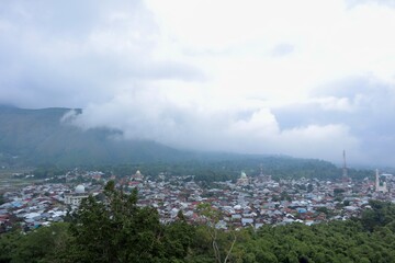 Fototapeta premium MistShrouded Townscape A mountain town veiled in clouds domes rising amidst a sea of rooftops and trees