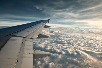 Obraz premium Airplane wing and clouds create breathtaking scene from above, inspiring sense of freedom and wonder as aircraft soars high