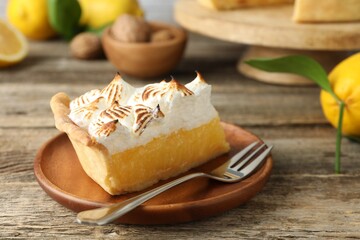 Piece of delicious pie with browned meringue and fork on wooden table, closeup