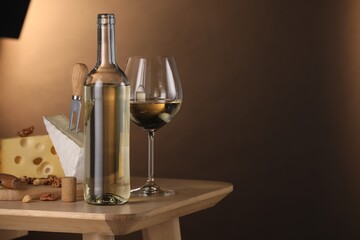 Tasty wine and snacks on wooden table against brown gradient background. Space for text