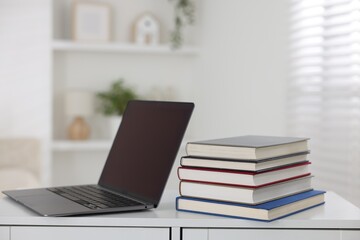 Different book and laptop on white desk indoors. Space for text