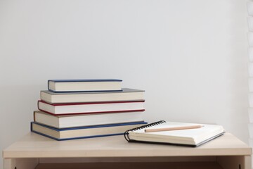 Books, notebook and pencil on wooden table indoors. Space for text