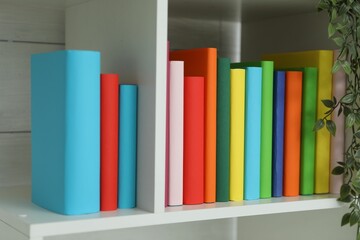 Colorful books on shelving unit indoors, closeup