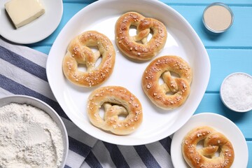 Tasty pretzels and ingredients on light blue wooden table, flat lay