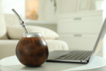 Traditional yerba mate tea and laptop on white table indoors