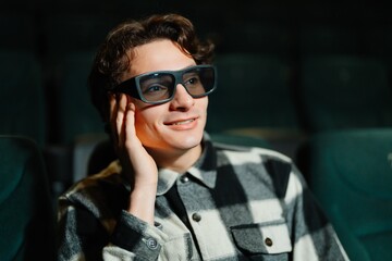 Young man enjoying a movie in stylish glasses at a theater