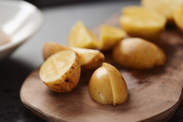 Raw washed and chopped baby potatoes ready to cook on olive wood board