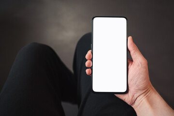 pov shot of man hand hold phone with white screen in dark interior