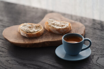 Espresso in blue cup with sandwiches with cream cheese on background