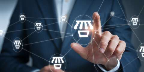 Person interacting with a digital network of shop icons, showcasing online business, e-commerce, and retail connectivity, symbolizing global market reach and digitalization