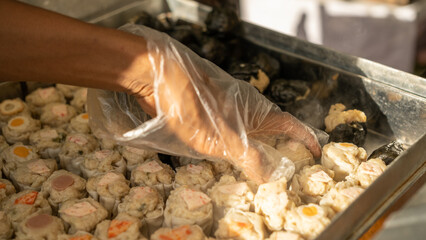 Fresh steamed dim sum being arranged by hand with gloves, showing hygiene and authentic Asian...