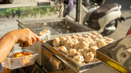 Close-up of traditional dim sum being served from a street food stall, highlighting local culinary...
