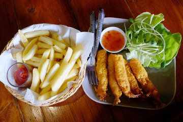 Fried shrimp with vegetables and french fries with sauce on white plate