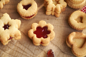 Filling star and flower shaped Linzer Christmas cookies with strawberry marmalade