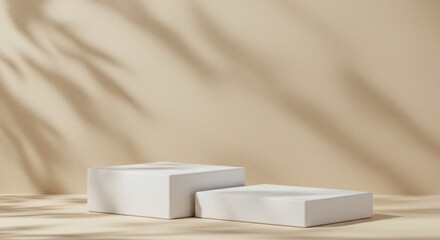 Two white cube podiums on a beige surface with shadow of leaves.