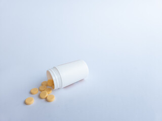 Vitamin B tablets and a white supplement bottle on a white background