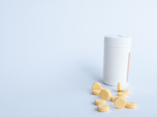 Vitamin B tablets and a white supplement bottle on a white background