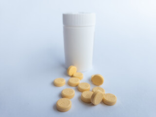 Vitamin B tablets and a white supplement bottle on a white background