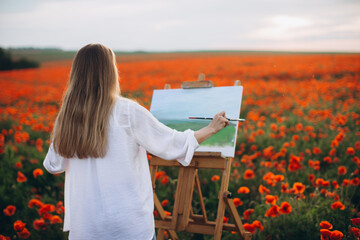 Woman painter painting a landscape in beautiful poppy field