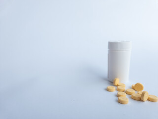 Vitamin B tablets and a white supplement bottle on a white background