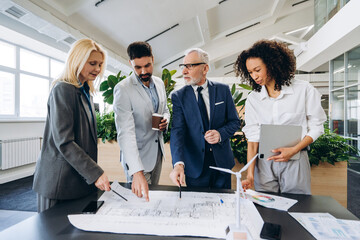 Engineers analyzing blueprint for sustainable building project, startup