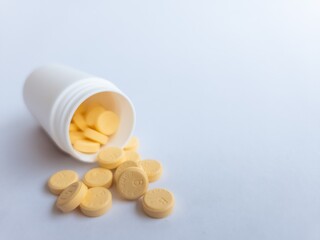 Vitamin B tablets and a white supplement bottle on a white background