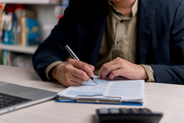Businessman working on official paperwork, signing documents with a pen at the office desk, representing business contracts, legal agreements, and document validation.