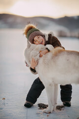 A BOY HUGS HIS HUSKY TIGHTLY IN WINTER