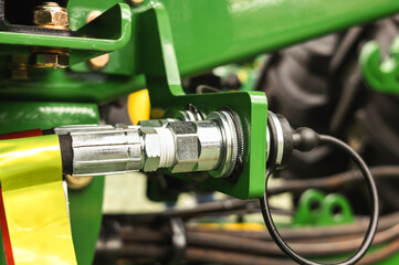 High pressure hydraulic coupling on a green tractor structure, highlighting the precision and resistance of the components used in agriculture.