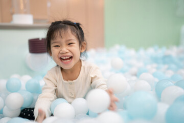 Joyful girl laughing in ball pit at indoor playground