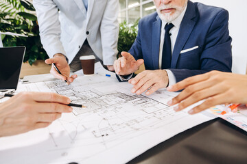 Architects and engineers discussing blueprint on table in office