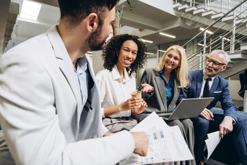 Multinational business people discussing charts and reports in office lobby