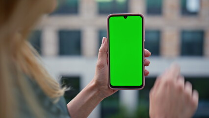 Entrepreneur scrolling greenscreen cellphone at architecture background closeup