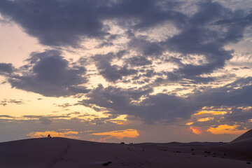 Beautiful clouds sunset sunrise with beautiful date palm tree in the desert sand dune Oasis