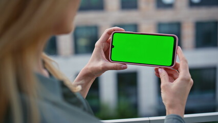 Hands holding horizontal chromakey mobile phone at city closeup. Woman online