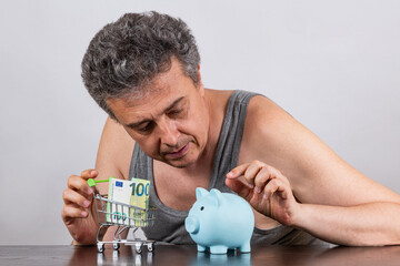 Conceptual story about poverty with a grey-haired middle-aged man, 100 euro bill and miniature...