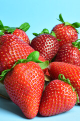 Close up. Strawberries in a kraft paper bag, on a light blue background. Vertical shot.