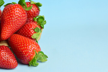 Close up, strawberries in a kraft paper bag, on a light blue background and copy space.