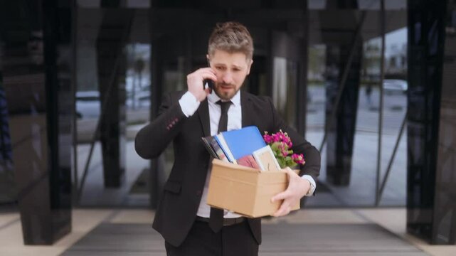 Man stressed on phone while leaving office after job termination