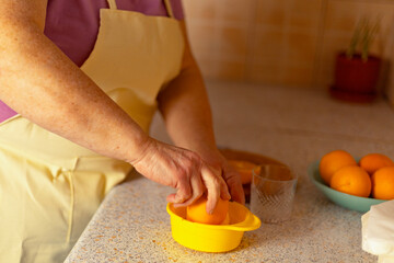 A woman's hand presses half an orange into a juicer