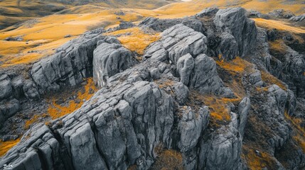 Rugged terrain on mountain peaks in a glacial valley, dark blue-grey rocks and yellow grass