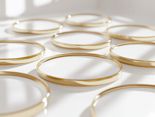 Collection of gold bangles arranged on a white surface illuminated by natural light